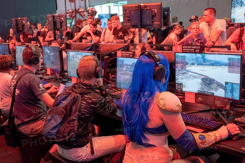 Female visitor in cosplay costume sitting in front of a military computer game