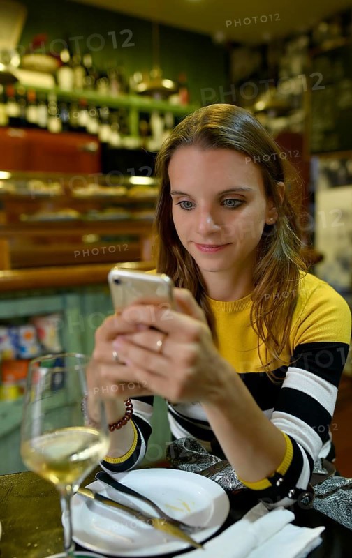 Young woman looks at her mobile phone in Tapas Bar
