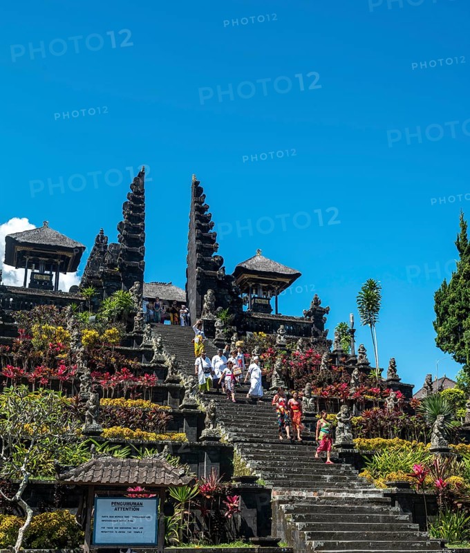 Balinese believers in traditional clothing go down stairs