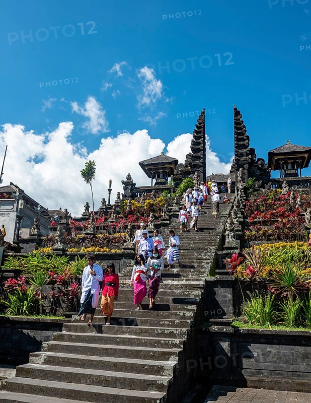 Balinese believers in traditional clothing go down stairs