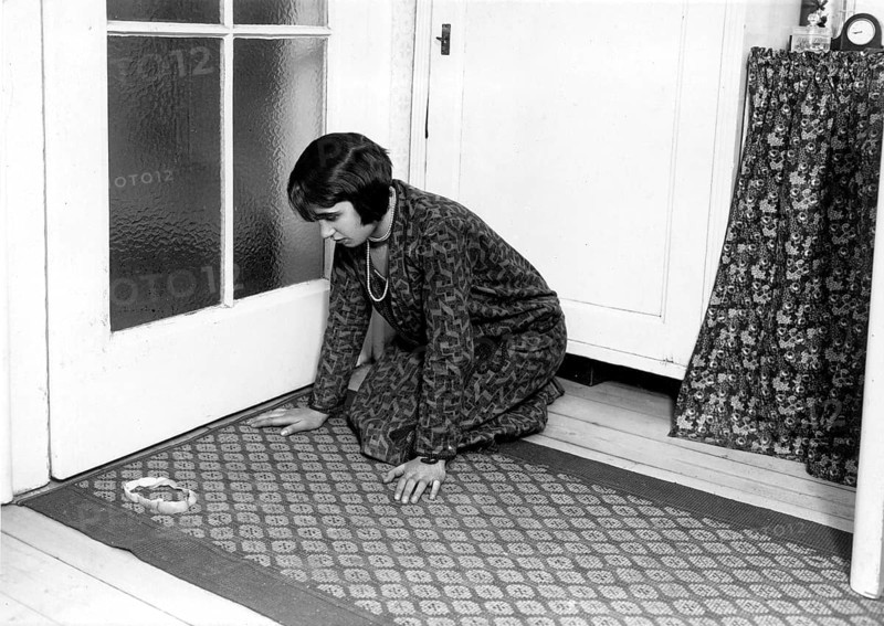 Woman kneels on the ground in front of an apple peel ca. 1927 superstition