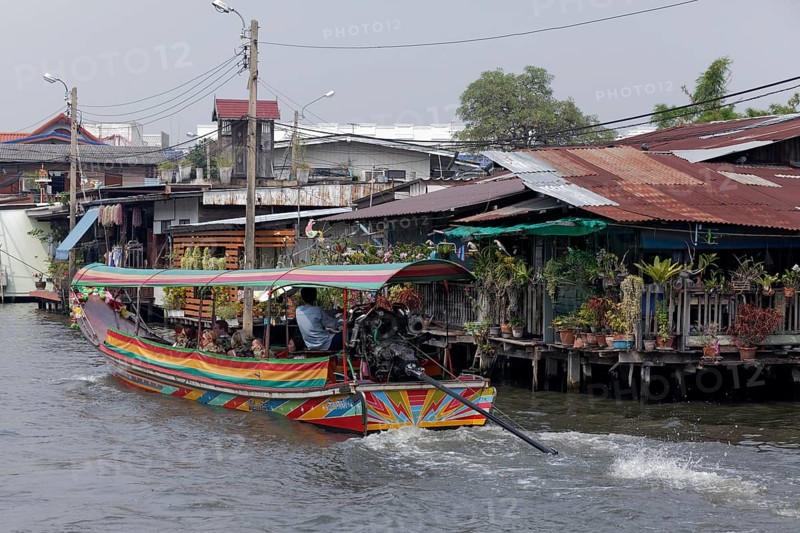 Canal with longtail boat and wooden houses on stilts