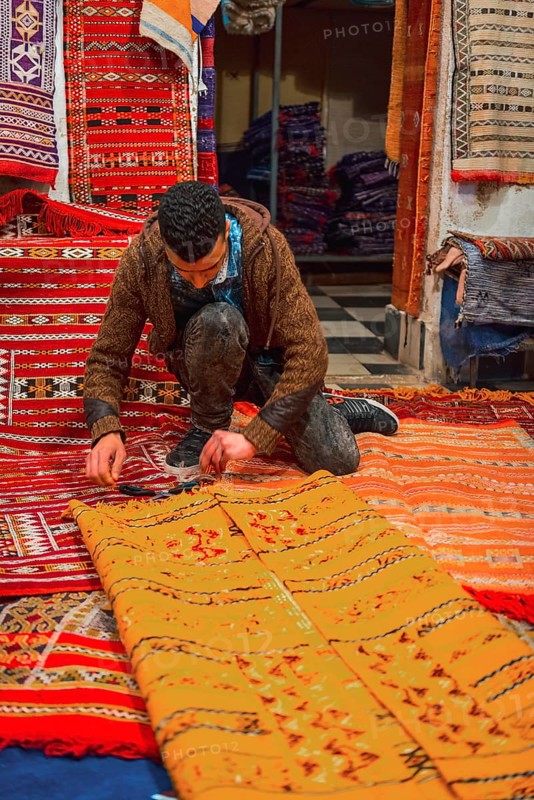 Carpet dealer folds a Moroccan carpet