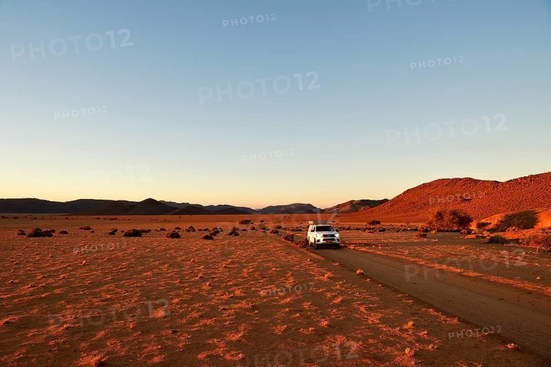 All-terrain vehicle drives on sandtrack in the evening light