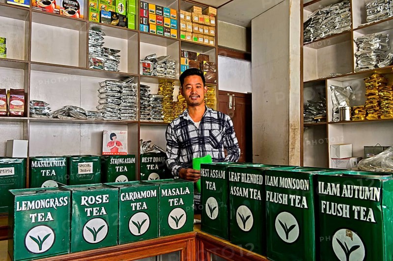 Tea merchant behind large tins with tea in his shop