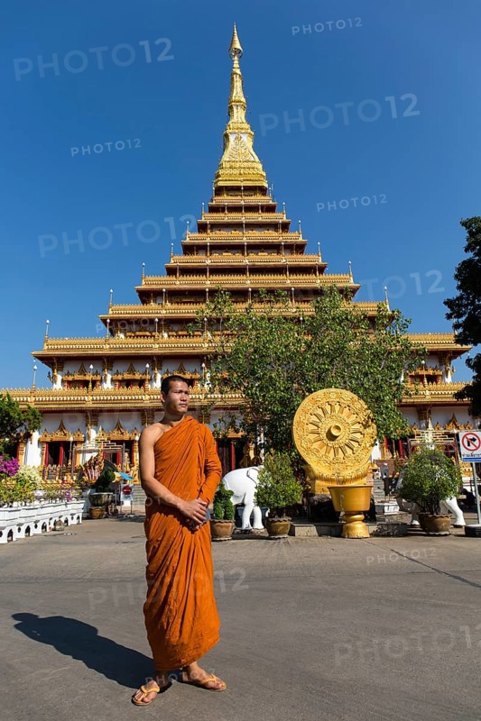 Buddhist monk stands in front of nine-story stupa Phra Mahathat Kaen Kakhon
