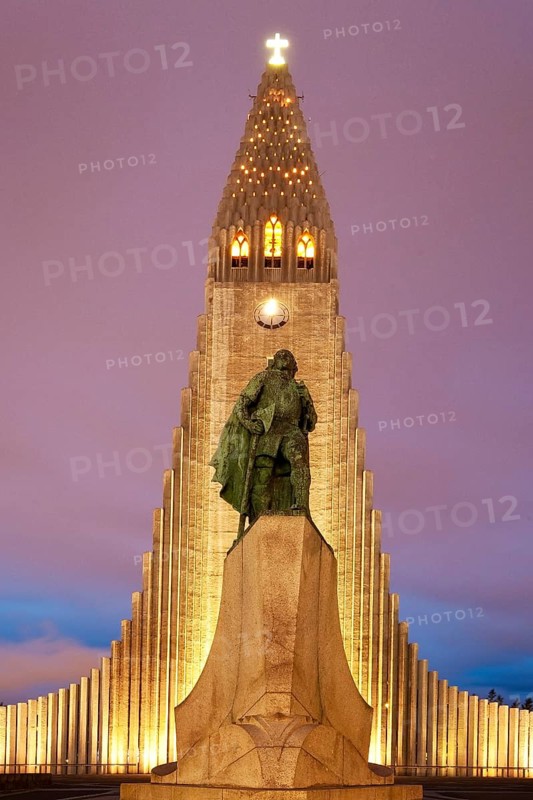 Illuminated Hallgrimskirkja with statue of Leif Eriksson at dusk