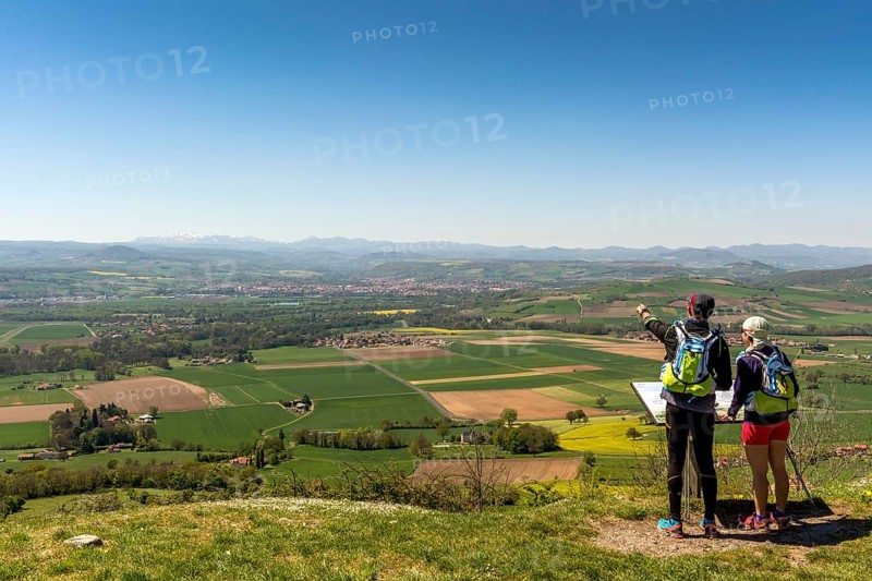Hikers enjoying the view from Usson village on plain of Limagne and the volcanic landscape of the Chaine des Puys