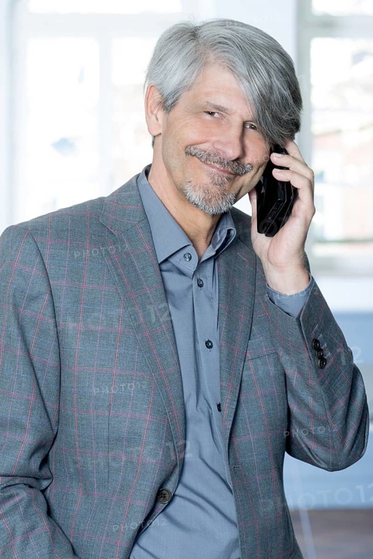 Man with mobile phone in front of his office window