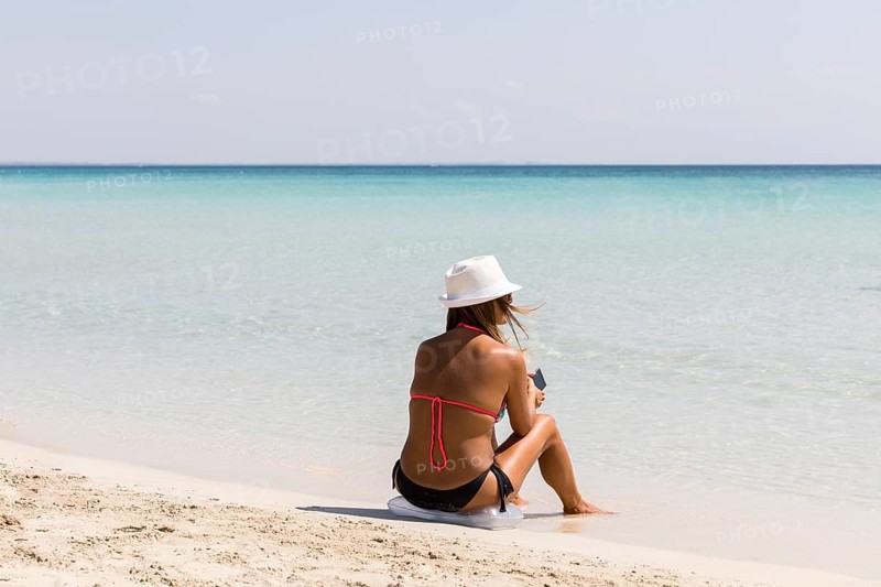 Woman sitting down by the sandy beach