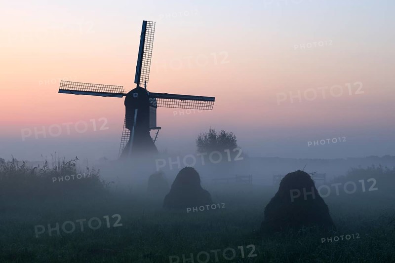Historical windmill in the early morning mist at dawn