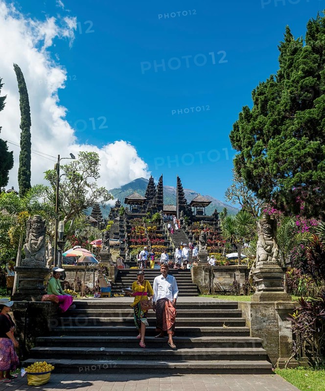 Balinese believers in traditional clothing go down stairs