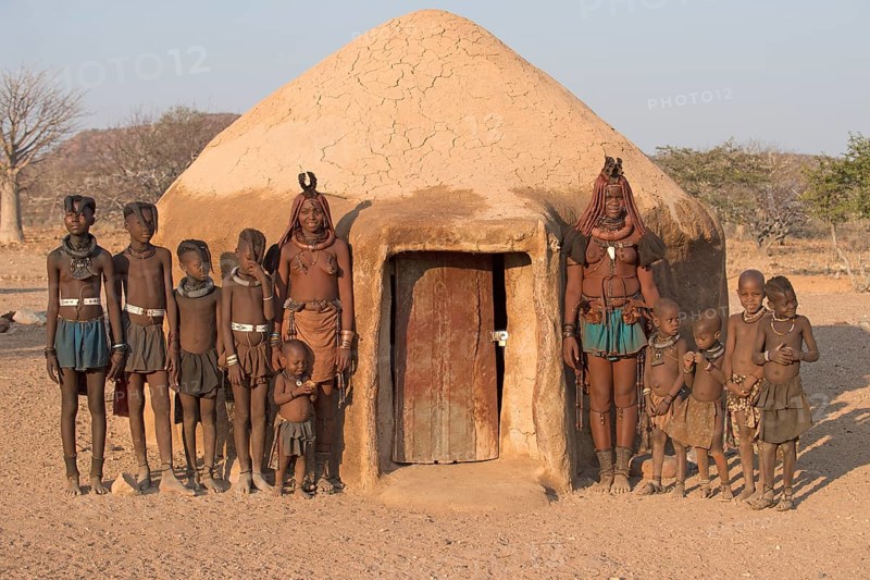 Himba women and children in front of a mud hut