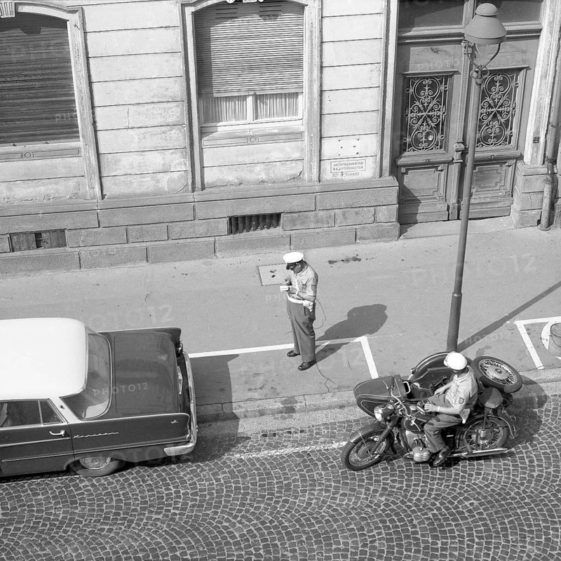 Two traffic policemen handing out a parking ticket to a car parker around 1950