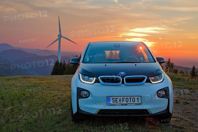 BMW electric car type i3 at the wind farm at sunset
