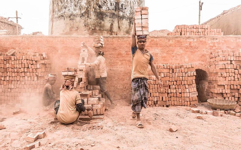 Workers with bricks on their heads in the brickyard