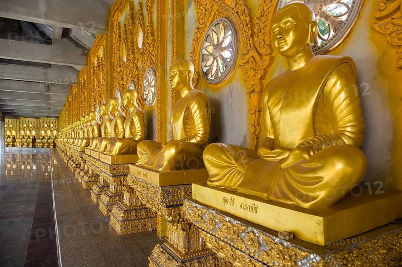 Row of golden Buddha statues in the corridor of the Phra Maha Chedi Chai Mongkhon Pagoda
