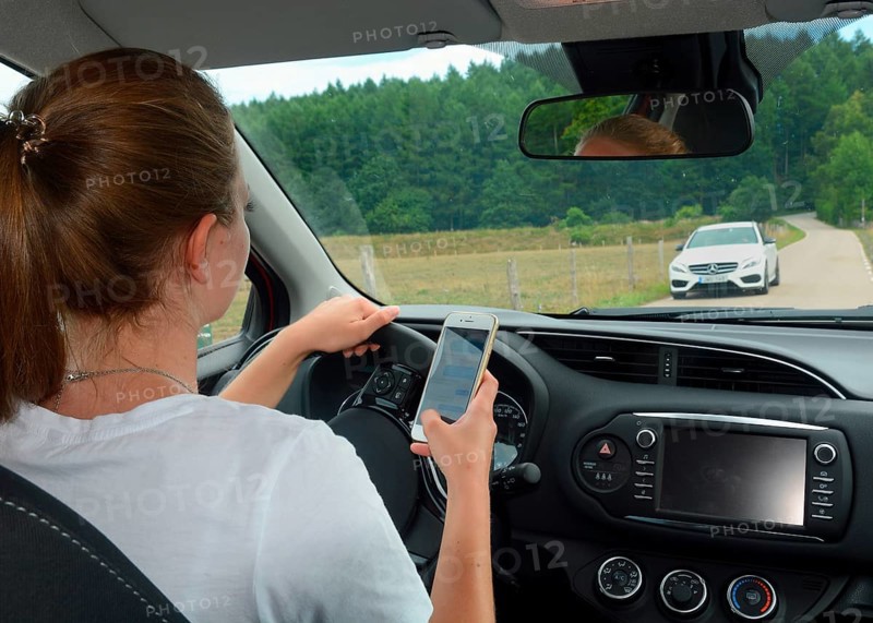 Young woman using a mobil phone while she drive a car