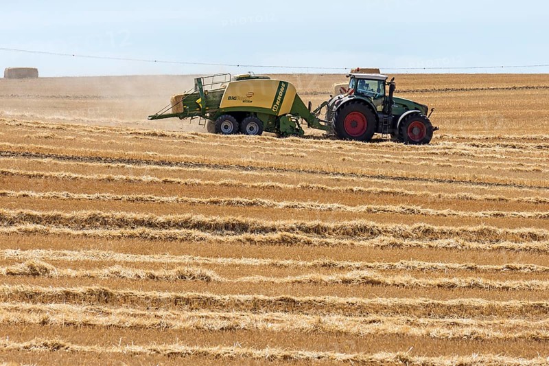 Tractor with straw baler on a mown wheat field