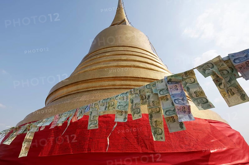 Thai banknotes are hanging on a leash in front of the golden Chedi
