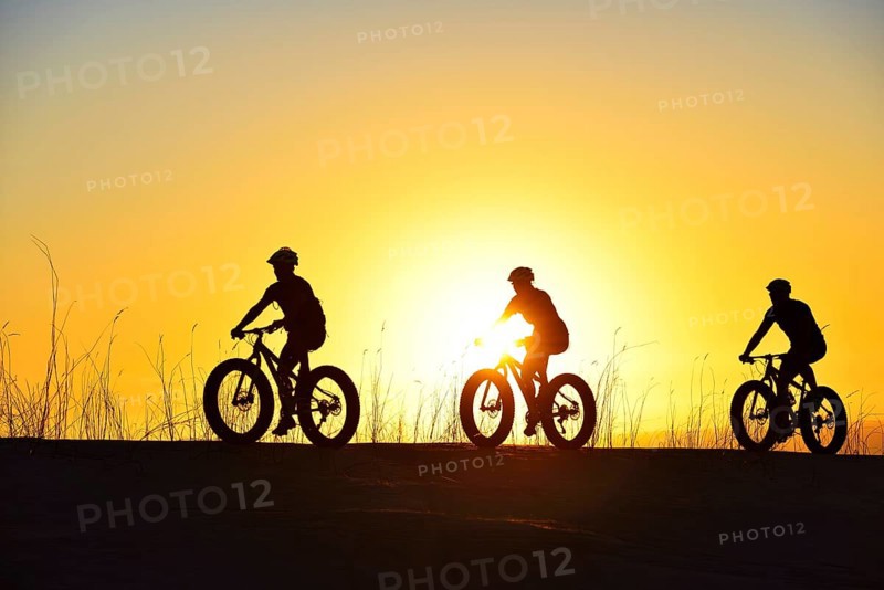 Mountain bikers with Fatbikes in the back light with sunset