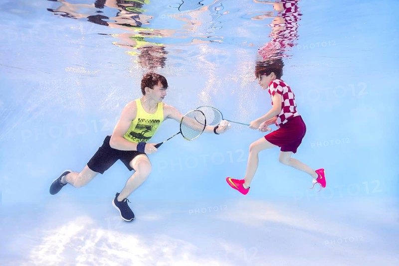 Two teenagers playing badminton underwater