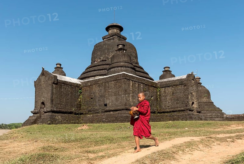 Novice Buddhist monk collects morning alms in front of Laymyetnha Paya