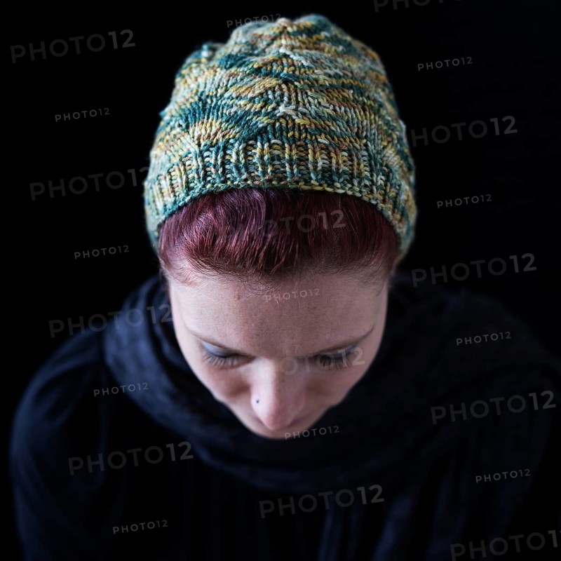 Woman with lowered head and green wool hat