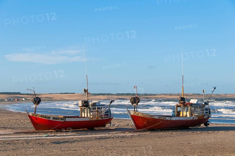 Two red fishing boats lie on the beach of the Atlantic Ocean