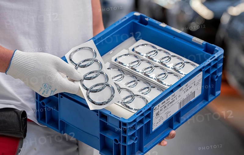 An Audi employee holds a box of Audi logos on the Audi A4 assembly line at the Audi AG plant in Ingolstadt