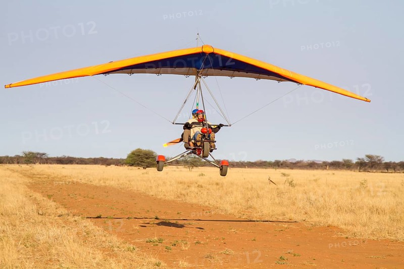 Ultra-light plane flying over sandy runway
