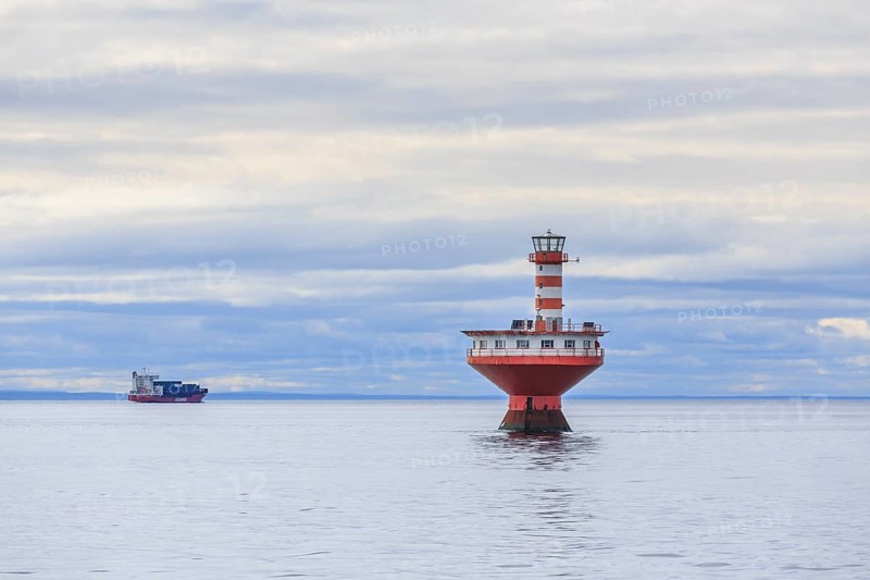 Lighthouse Phare du Haut-Fond Prince in Saint Lawrence River with freighter in the back