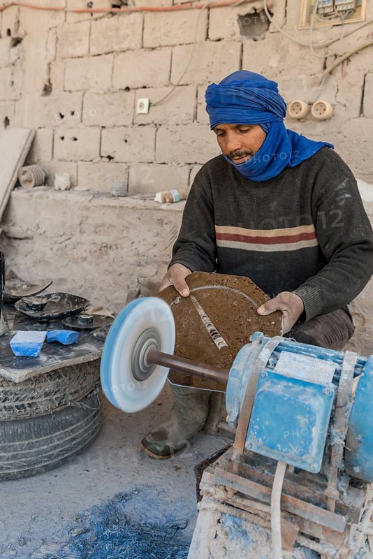 Bedouin preparing stone slabs with fossils