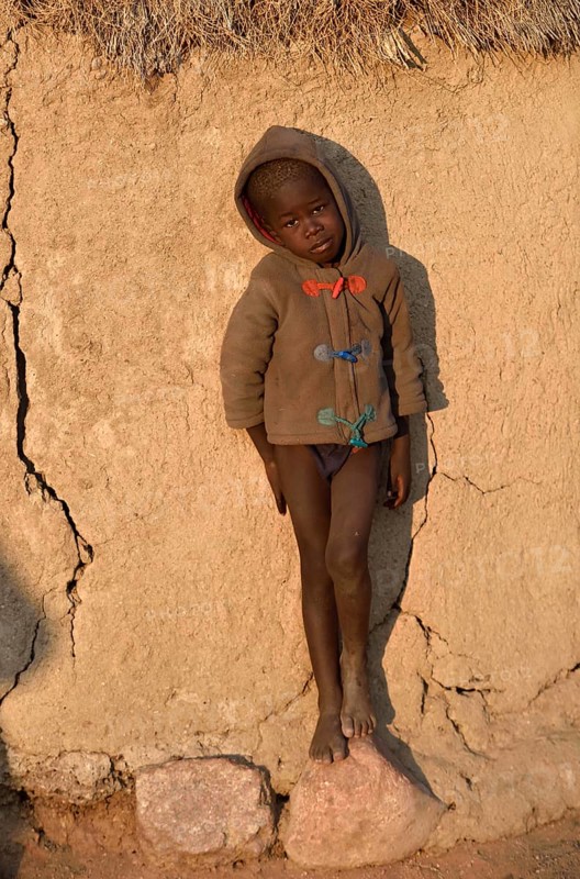 Himbajunge leans on mud hut