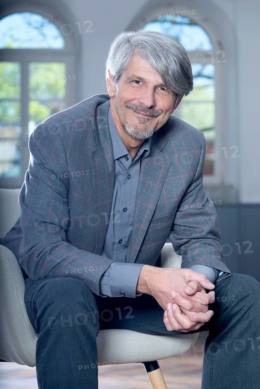 Man sits smiling in an armchair