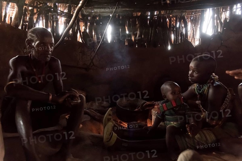 Family sits in mud hut