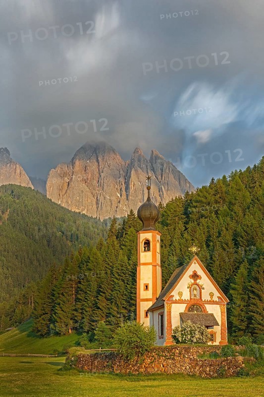 Church of St. Johann with cloudy Geislerspitzen in the background