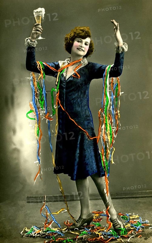 Woman celebrates New Year's Eve with champagne and paper snakes