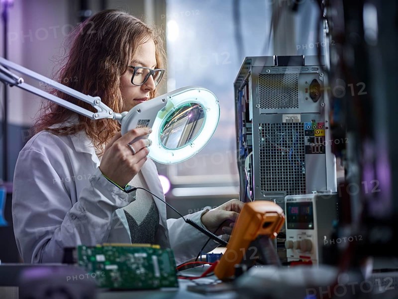 Technician with white lab coat with a measuring device in an electronics laboratory