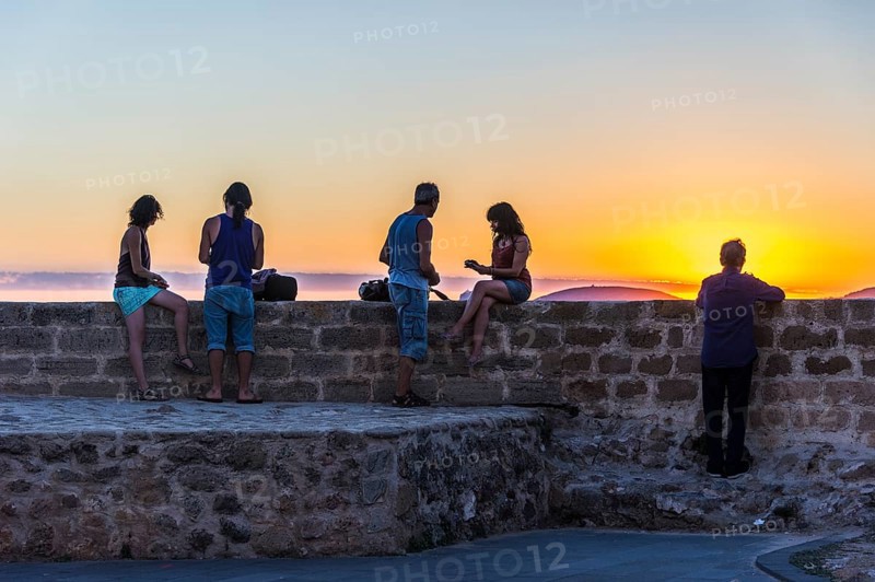 Tourists enjoying sunset at the waterfront of the coastal town Alghero
