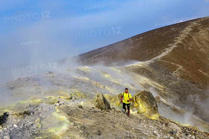 Trailrunner surrounded by sulfur fumaroles and chloride crusts on the crater rim
