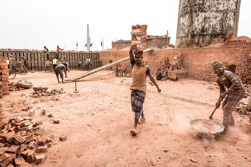 Workers with bricks on their heads in the brickyard