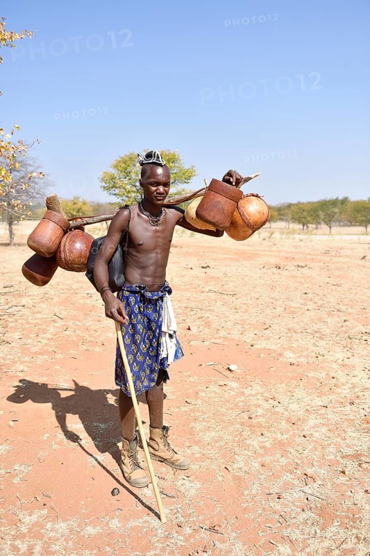 Young Himba man carries food on the cattle drive