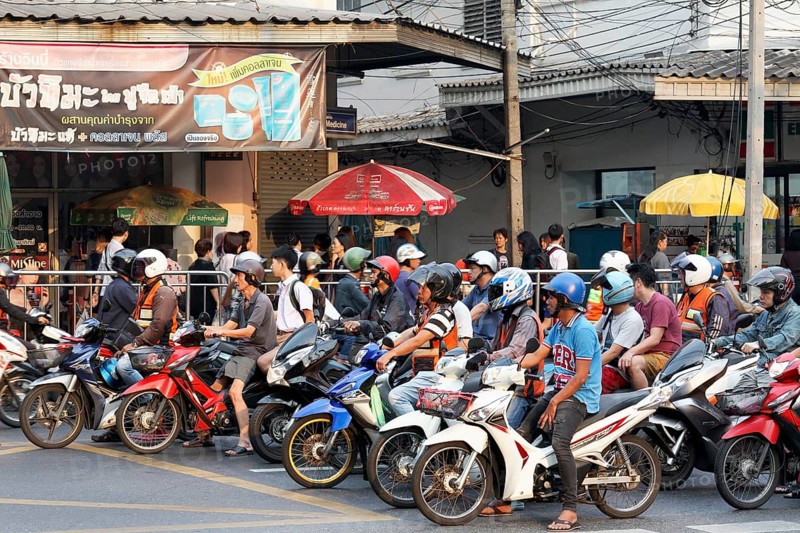 Many moped drivers are waiting at an intersection