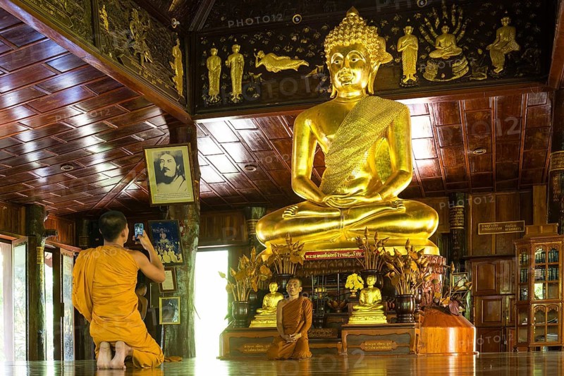Monks in front of golden Buddha statue