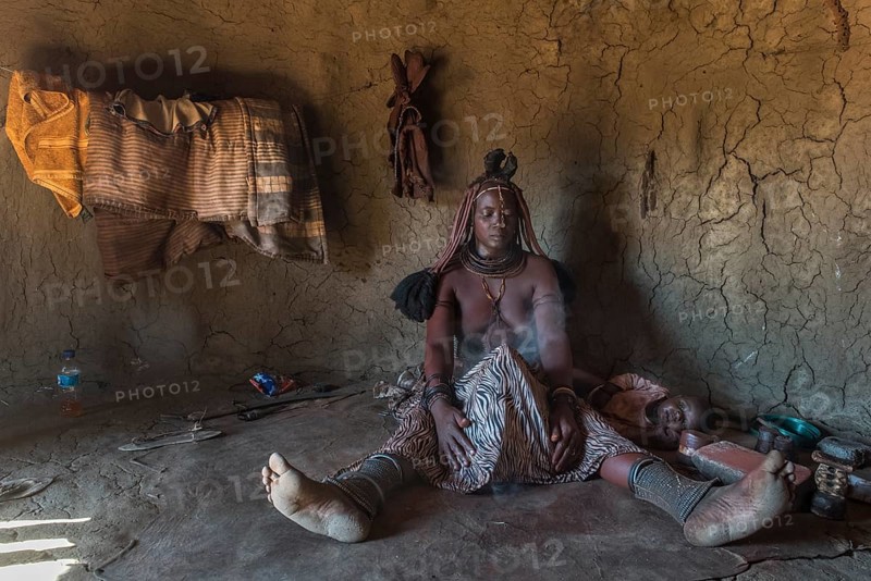Woman of the Ovahimba or Himba people cleaning and disinfecting clothes and body