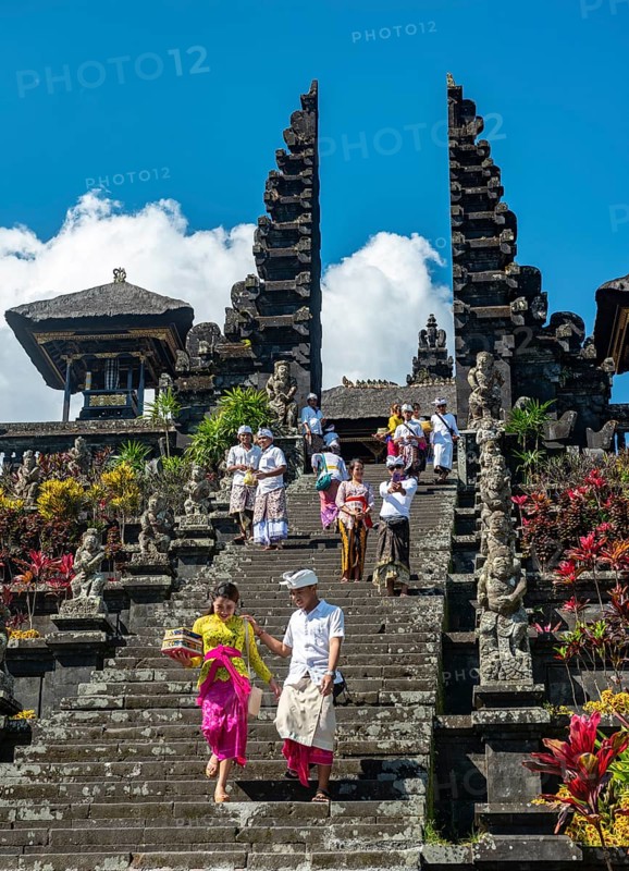 Balinese believers in traditional clothing go down stairs