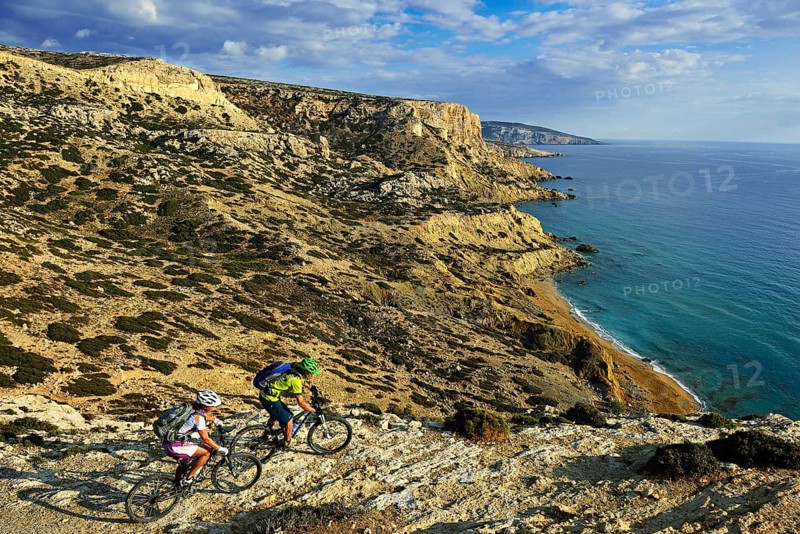 Two mountain bikers cycle along the rocky coast