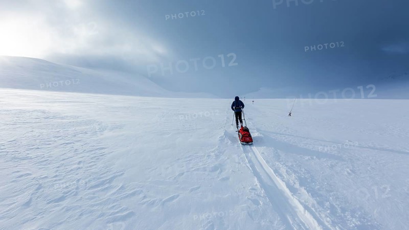 Ski tourer with pulka in the snow
