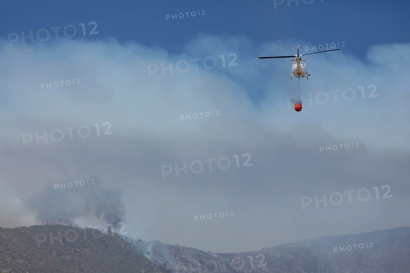 Helicopter flies with an extinguishing water tank to a fire